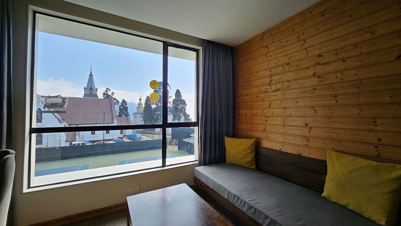 An image of a deluxe room with a couch, a table, and an expansive window - Yashshree Sanderling, Darjeeling