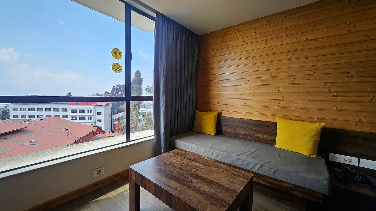 An image of a premium room featuring a couch, a table, and an expansive window overlooking the view outside - Yashshree Sanderling, Darjeeling