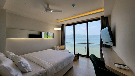 Side view of a single bed facing the ocean with a wall mount TV on the side in the 6ix Sea View Room at 6ix Seashore Hotel, Port Blair
