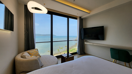 View of half a double bed, a small sofa facing the TV in the 6ix sea view room with Jacuzzi at 6ix Seashore Hotel, Port Blair