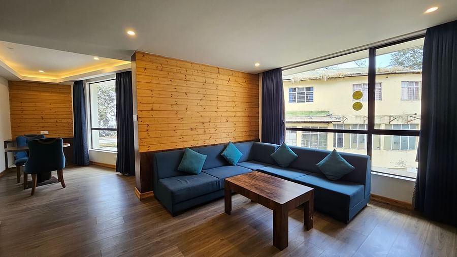 An image of a deluxe suite featuring the living area with sofa set, table and expansive windows overlooking the view - Yashshree Sanderling, Darjeeling