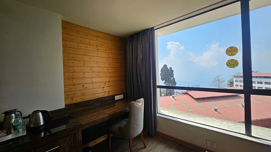 An image of a premium room featuring a work desk, a chair, room amenities, and an expansive window overlooking the view - Yashshree Sanderling, Darjeeling