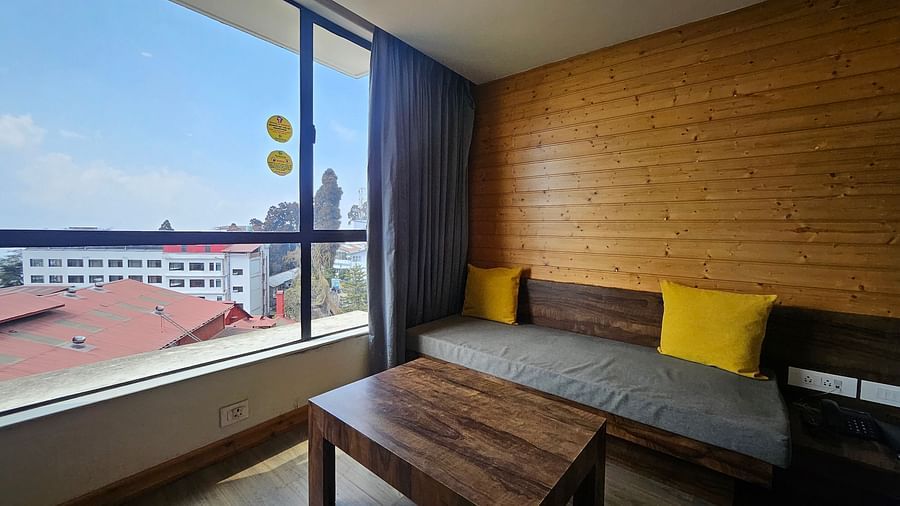 An image of a premium room featuring a couch, a table, and an expansive window overlooking the view outside - Yashshree Sanderling, Darjeeling