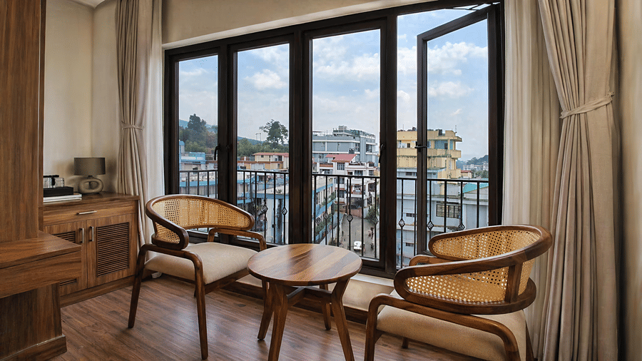 A Premium Room at Valmere Chery Blossom Suites featuring wooden armchairs with woven backs, a small coffee table, and a clear view outside.