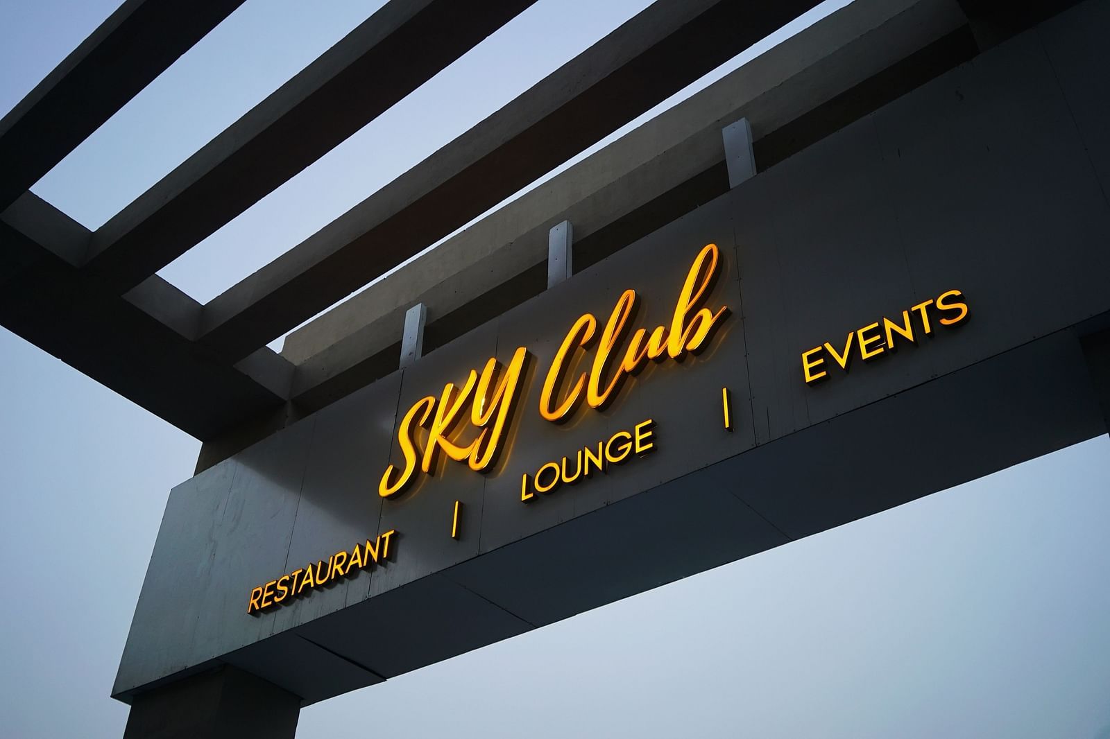 A view from below of Sky Club Signage with clear sky in the background.