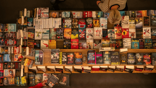 A shop wall is completely covered in various books and magazines for sale.