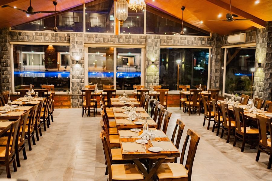 Restaurant interior featuring large windows and a warm dining space with well-arranged tables - Mastiff Grand La Villae Resort, Lonavala