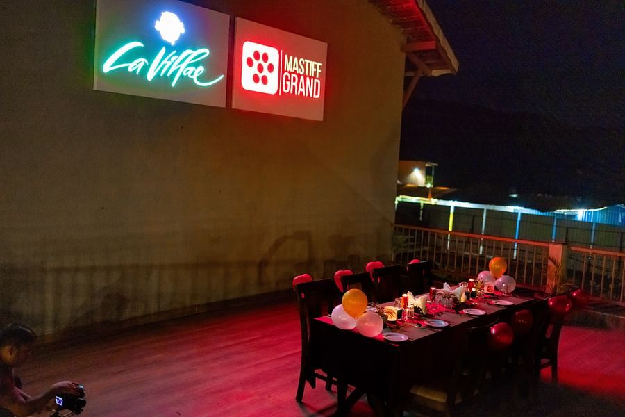 Outdoor seating area at the restaurant with tables arranged for an evening gathering - Mastiff Grand La Villae Resort, Lonavala