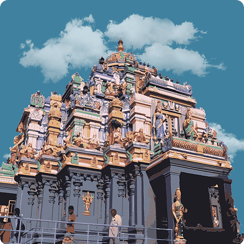 A majestic temple with richly carved reddish-brown gopuram and mythological motifs all around.