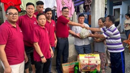 A group of people in red t-shirts gathered together, giving away a large basket to someone - Lords Hotels & Resorts