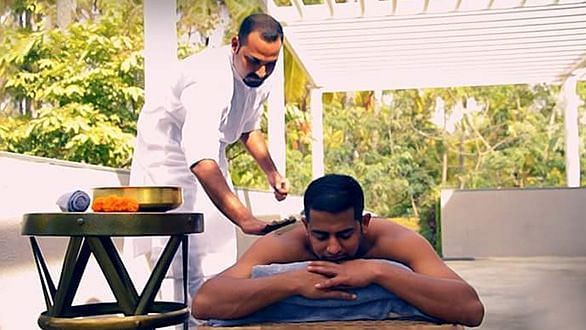 A person receiving a massage on a table outdoors, with another person standing - Shreyas Retreat