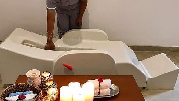 A white chair with candles and items on a tray, indoor setting - Shreyas Retreat