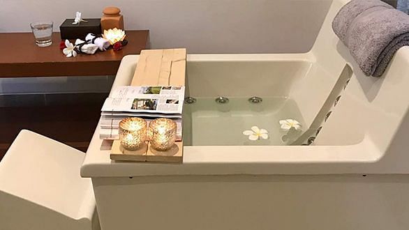 A bathtub with items arranged on a wooden tray, indoor setting - Shreyas Retreat