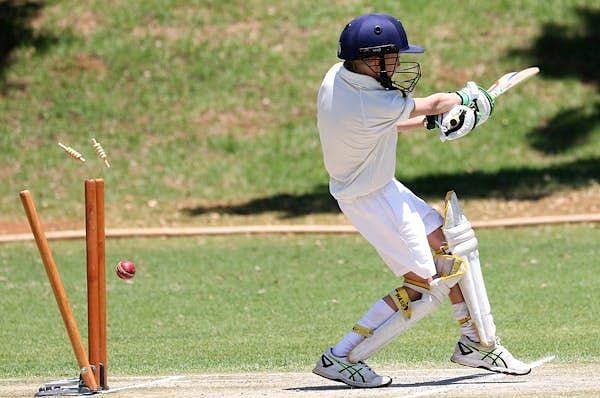 A close view of the cricketer batting on a green cricket field.