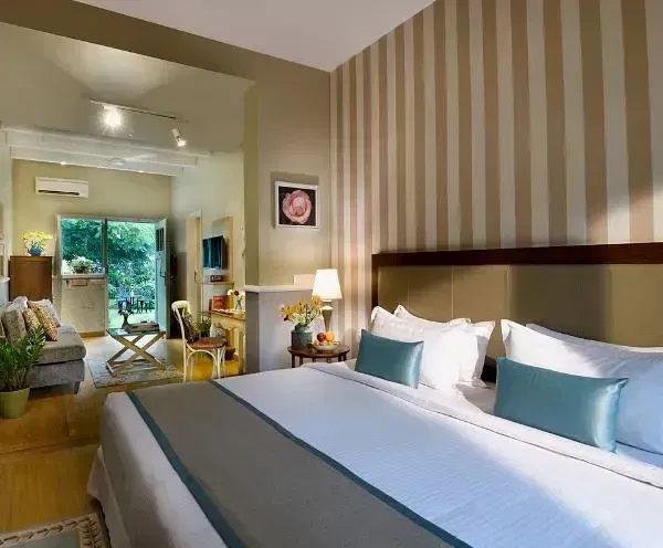 Stylish bedroom with blue and white bedding, striped wallpaper, and a mirror reflecting a seating area at Karma Chalets.