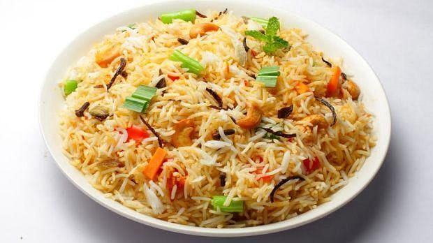 A plate of vegetable biryani topped with cilantro