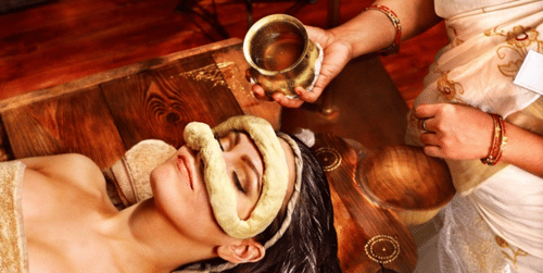 A woman lying with a dough ring around her closed eyes and a hand with a glass over her head at YO1 Longevity & Health Resorts