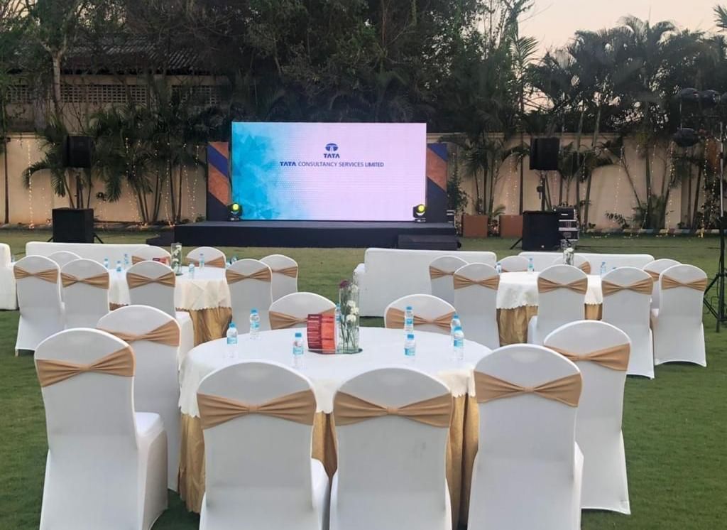 Round table banquet setup with white and gold chairs under natural lighting at Ilara Hotels & Spa, OMR, Chennai