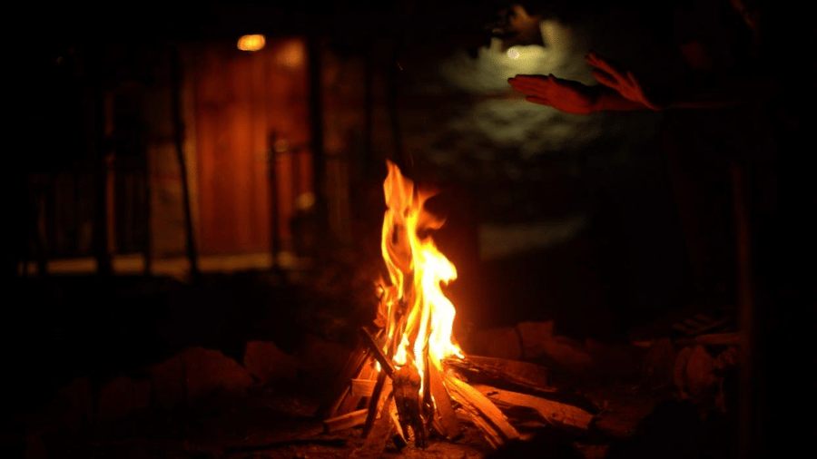 A bonfire burning brightly in the middle, with orange and yellow flames leaping up against a dark background at Amara Upepo - The Sky Village, Manali.