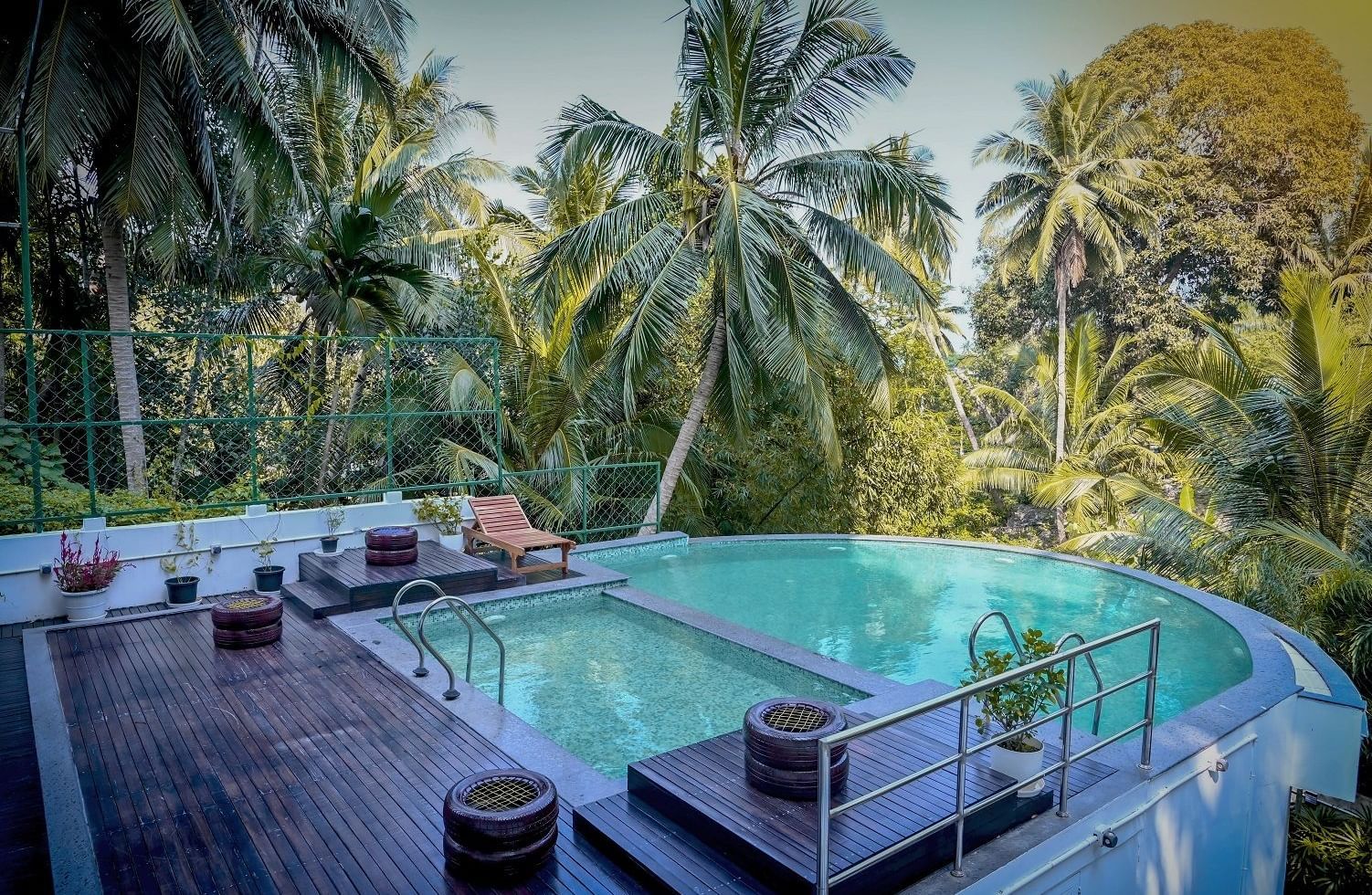 An outdoor swimming pool with clear blue water, surrounded by lush green tropical vegetation and trees - Sea Hills Hotels, Sri Vijayapuram (Port Blair)