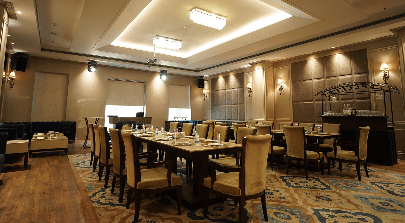 A spacious and modern banquet hall at Nirvana Luxury Hotel, Ludhiana, set with neatly arranged tables and chairs on a patterned blue carpet, ready for an event.