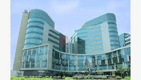 Multiple glass fronted hospital buildings featuring landscaped greenery.
