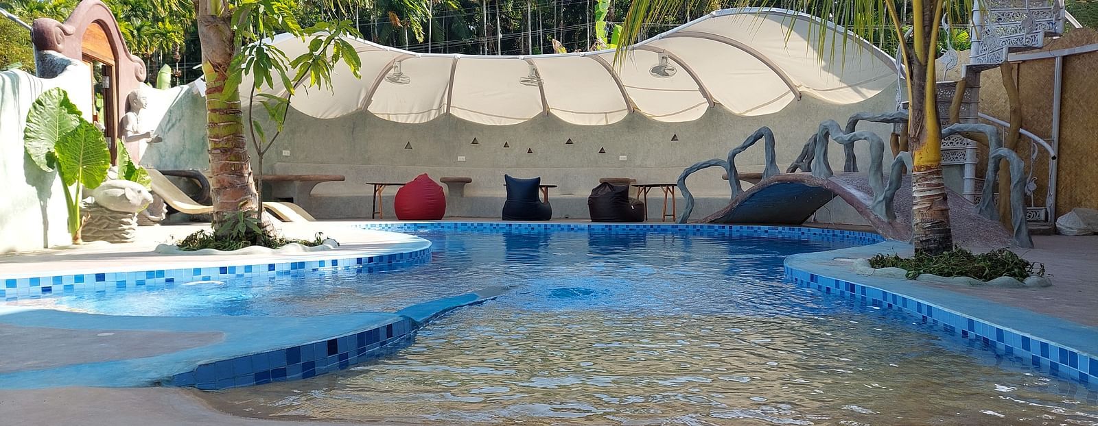 Serene poolside oasis with abundant tropical plants on a sunny day at Matsya Island Retreat by Island Quest.