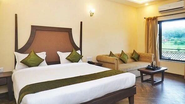 A double bed and sofa inside Regalia Bathtub Room at Rahi Forest View
