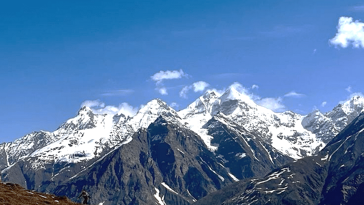 Majestic snow-covered Himalayan mountain range under a clear blue sky.