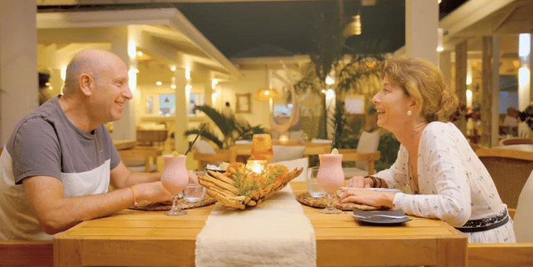 Smiling couple enjoying a candlelit dinner at a warmly lit restaurant.
