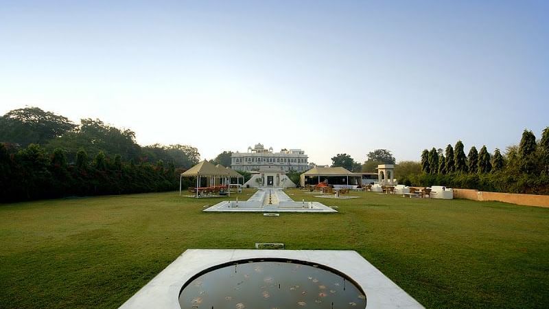Expansive garden with water features, seating tents, and a grand heritage building in the backdrop at Ram Pratap Palace, Udaipur.