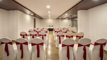 Banquet hall setup featuring  ample seating arrangement, bright lighting, and wooden flooring at Lords Eco Inn Jayanagar Bangalore.