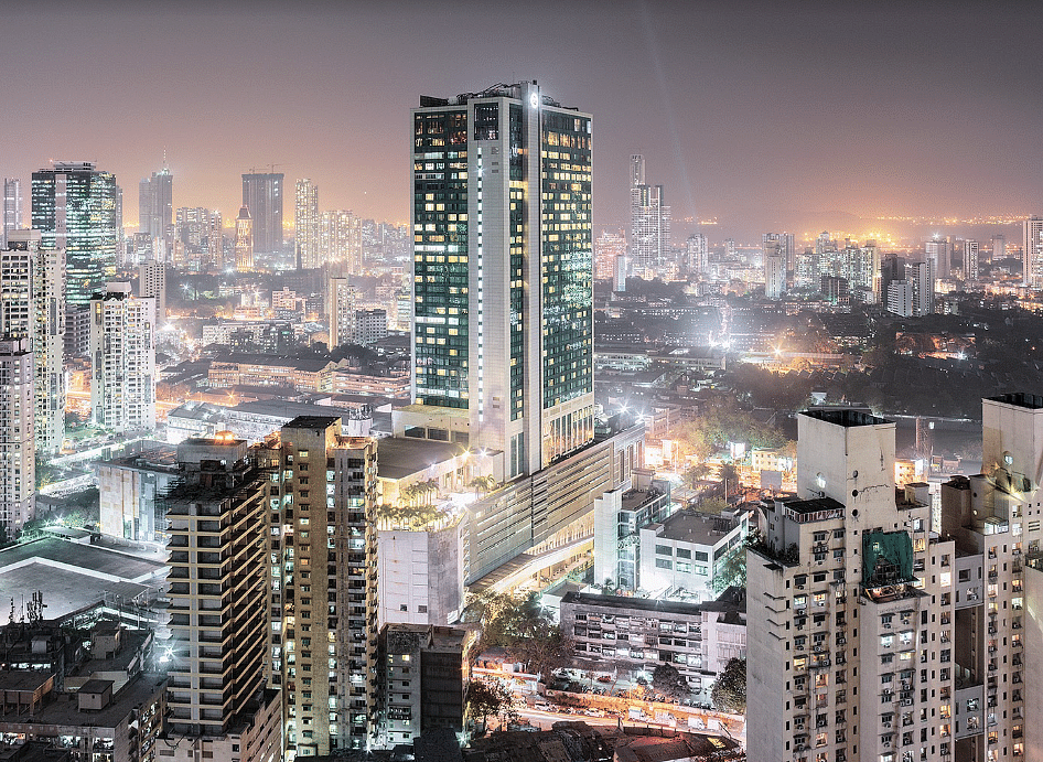Mumbai skyline at night with illuminated skyscrapers and city lights.