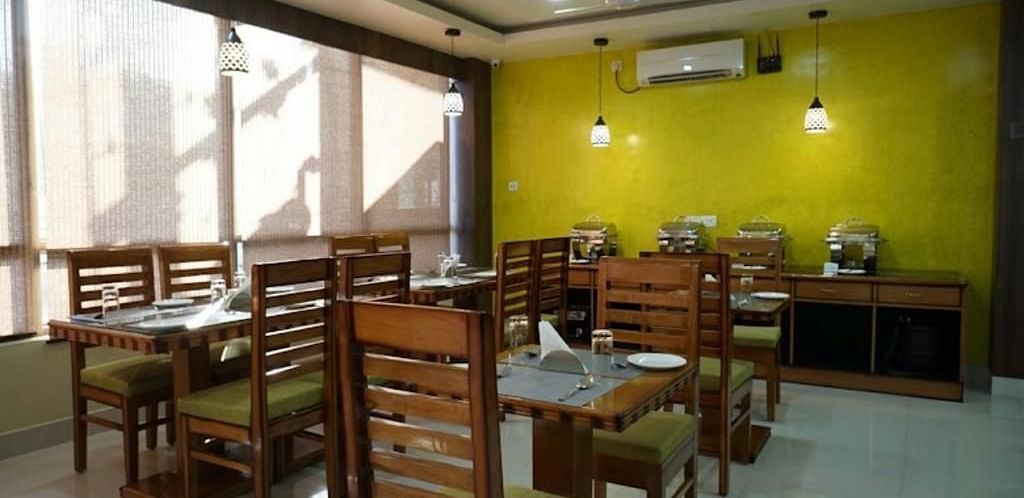 A brightly lit dining space with wooden tables and chairs, perfect for relaxed meals - Pemaling Lords Eco Inn Guwahati