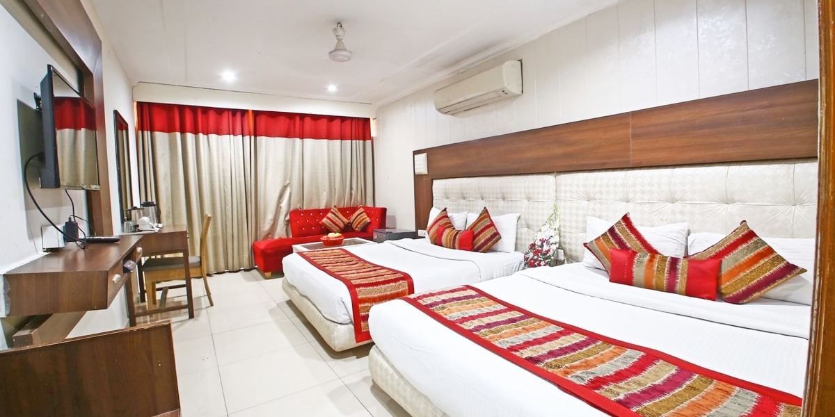 Family Room featuring a work desk, large window with curtains, and two queen size beds -  Hotel Diamond Plaza, Chandigarh.