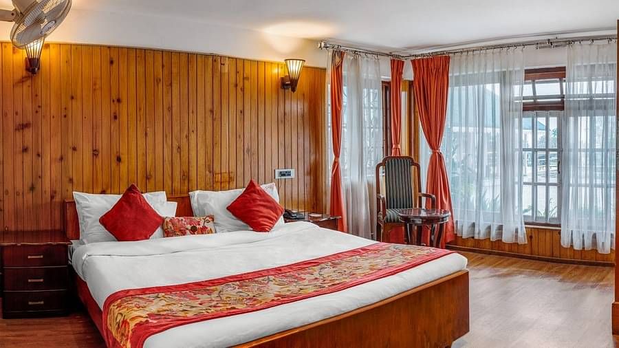 A room at Summit Barsana Resort & Spa, Kalimpong with a double bed and large windows
