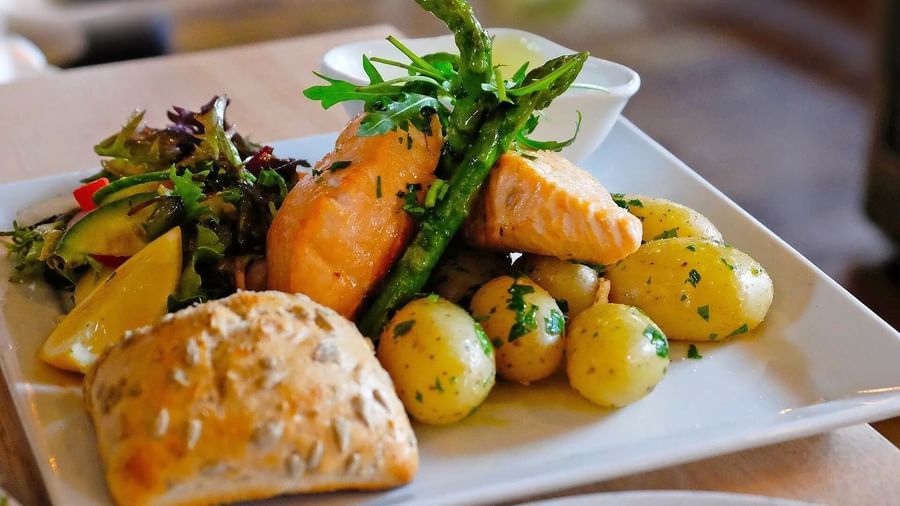 A plate with a main course including roasted vegetables, a bread roll, and a side salad | Altamont Court, Jamaica