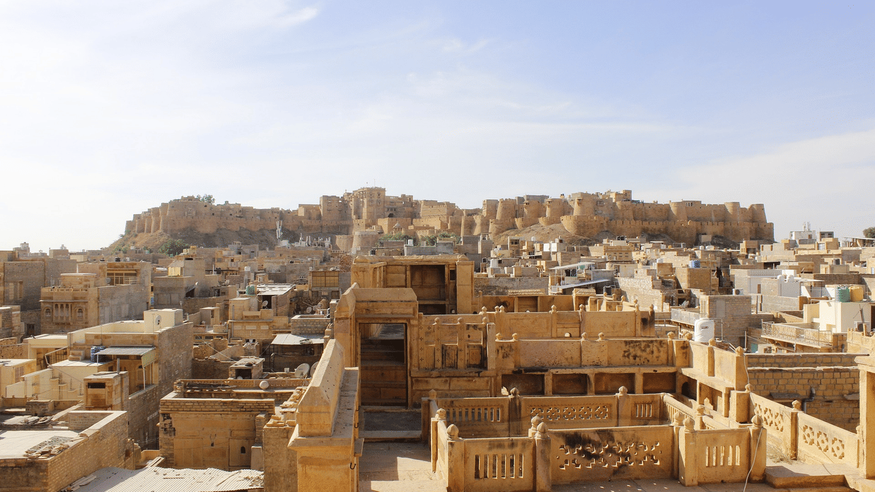 Panoramic view of the historic golden sandstone Jaisalmer Fort rising above the traditional stone rooftops of the old city.