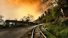 Train track through the mountains with small shops along the side, under a sunny yet foggy and chilly sky