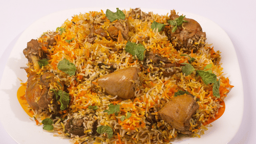 A plate of biryani rice with meat is presented, showing a flavourful dish.