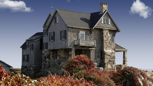 A facade of a stone house amidst colourful flowers