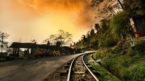 Train track through the mountains with small shops along the side, under a sunny yet foggy and chilly sky