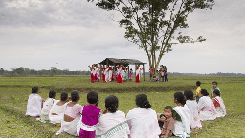 Women dancing in distance amidst grasslands