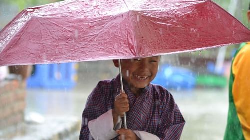 image of A small child holding an umbrella in pouring rainfall
