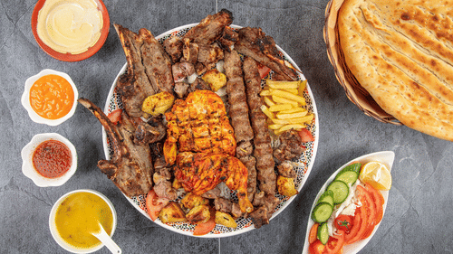 A mix grilled kebab platter with different sauces on the side