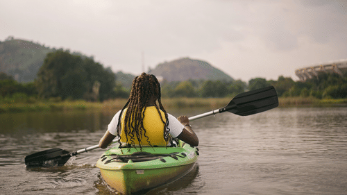 A girl kayaking in a water body surrounded by mountains