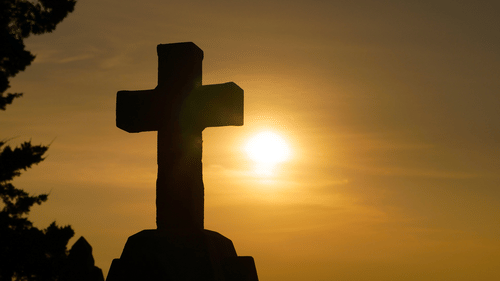 a close up shot of a Cross stone with the sunset in the background