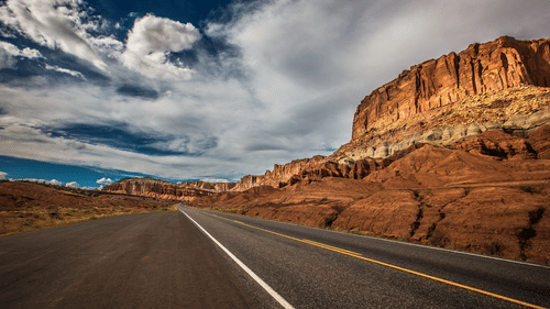 Image of a clear road on a bright day with a mountain on one side
