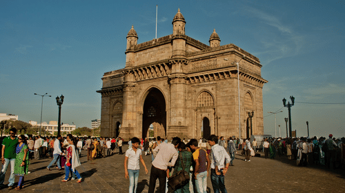 A stone gateway with people gathered in front, taking photos and walking.