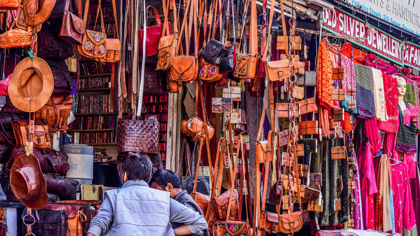 Local market stall displaying handcrafted leather bags, accessories, and colourful textiles.